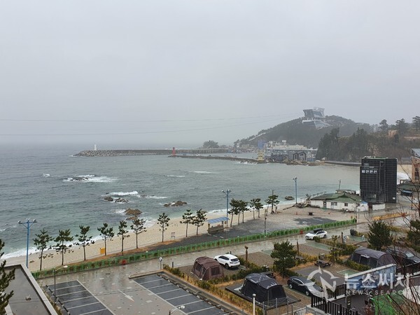  비 내리는 장호항. 장호항의 아름다운 풍광 덕분에 장호항은 ‘한국의 나폴리’라고도 불리운다. 장호항 뒤편에 삼척해상케이블카 승강장과 케이블이 보인다. 비가 상당히 많이 와서 파도도 높아 장호항 해변에 인적이 드물다.