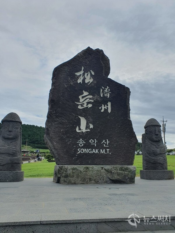 송악산 입구 표지석. 제주도 서귀포시 대정읍 상모리에 있는 송악산 주차장 인근 송악산을 오르는 입구에 검은 현무암으로 된 제주 송악산 표지석이 있으며, 표지석 양 옆으로 돌하르방이 보초를 서고 있다.