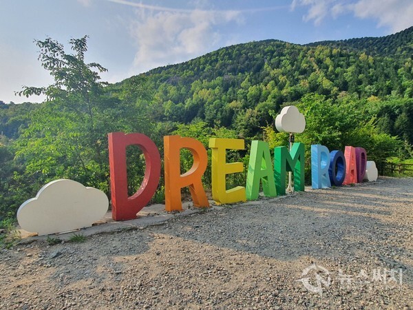장복 하늘마루길에 조성된 DREAM ROAD 영문조형물. 안민도로를 걷다보면 우측으로 갈림길이 나오는데 이곳으로 진입하면 진해드림로드의 두 번째 길인 ‘장복 하늘마루길’로 접어들게 된다. ‘장복 하늘마루길’은 안민도로 안민휴게소에서 시작하여 삼밀사 옆 장복산 입구까지 연결된 약 4km 정도 길이의 걷기길로 안민도로에서 하늘마루까지는 약간 경사가 있는 오르막길을 계속 올라가야 한다. 장복 하늘마누길을 걷다보면 길 바깥쪽에 알파벳으로 되어있는 DREAM ROAD 영문조형물을 볼 수 있다. 